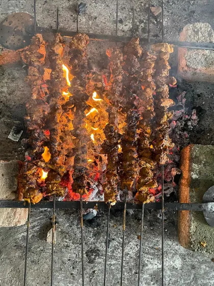 Banjara Chicken kebabs being grilled over an open flame. The direct heat gives these starters a delicious char and smoky aroma that you can't get from a regular oven.