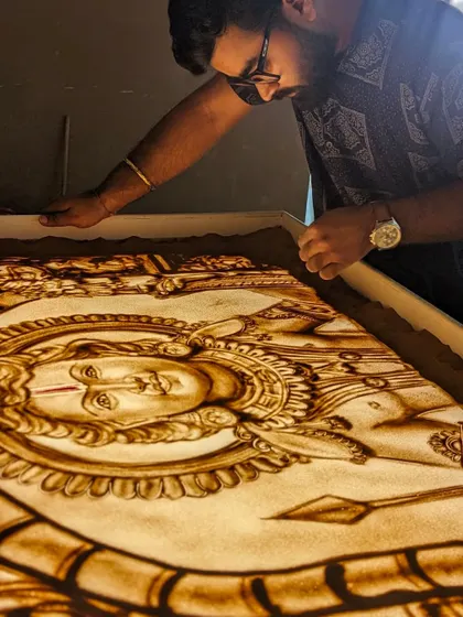 The final touches on a large-scale sand art piece. The light from the lightbox illuminates the sand, giving it a divine glow.