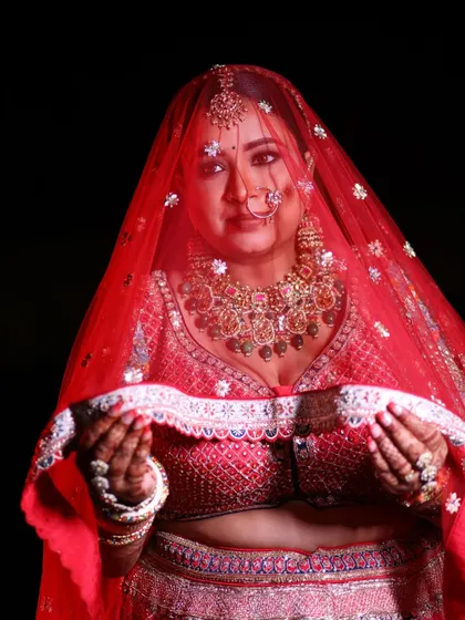 A classic bridal portrait, with the bride looking through her sheer red veil, full of anticipation and grace.