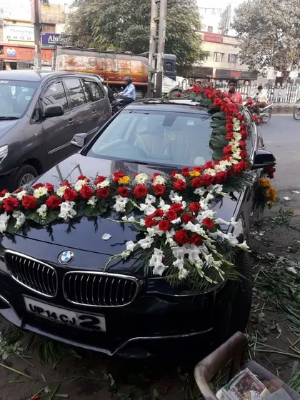 A premium BMW decorated with a garland of red and white flowers. I provide on-location service to decorate any car model, ensuring a royal look for the groom's arrival.
