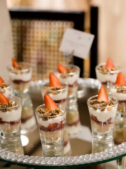 Strawberry and granola parfaits served in shot glasses. This is a light and elegant dessert option, perfect for brunches or as a refreshing end to a meal.