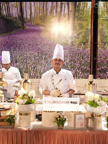 Meet the culinary maestros behind the magic. Our chefs at a live station, set against a beautiful floral backdrop, ready to create an unforgettable dining experience.