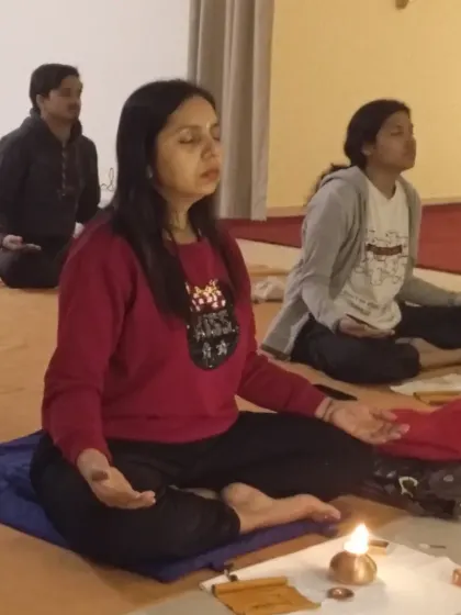 A close-up of a participant meditating with her ghee lamp, deeply involved in the process of elemental cleansing.