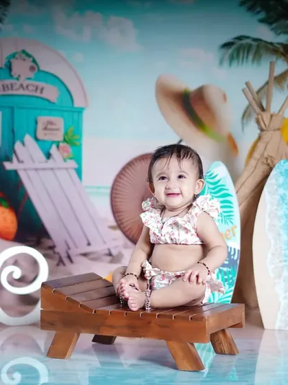 A day at the beach. This little girl is ready for some sun and surf in our beach-themed studio setup, complete with a beach hut and surfboards.