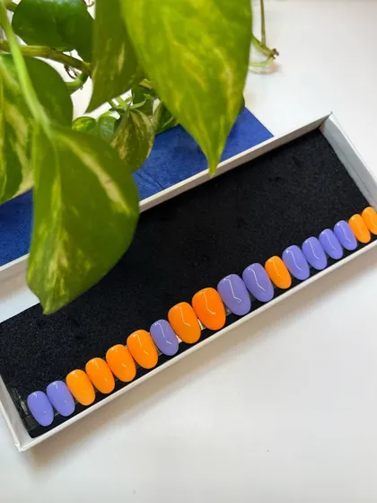 A vibrant and eye-catching color combination. This press-on set pairs bold orange with a lovely periwinkle purple for a look that's unexpected and fun.