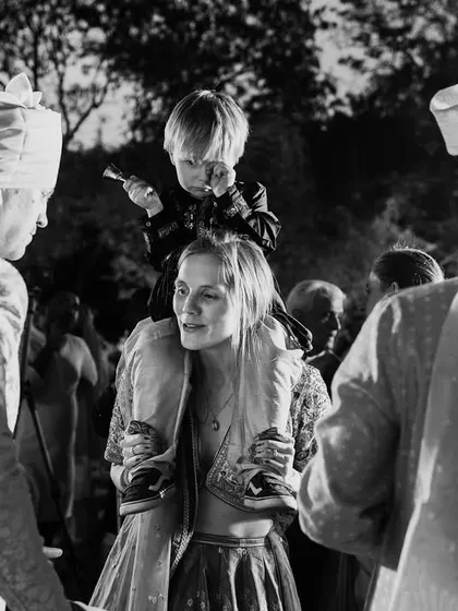 A fun black and white candid of a child on a guest's shoulders during the party. These are the joyful, chaotic moments that make a wedding memorable.