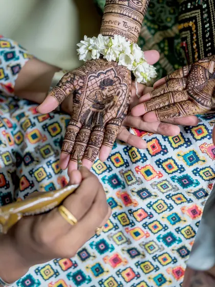 A close-up of the mehendi artist at work, meticulously applying a beautiful design that includes a portrait of the couple.