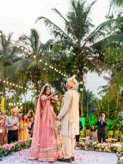 Another angle of the playful varmala exchange, capturing the bride's determined and happy expression.