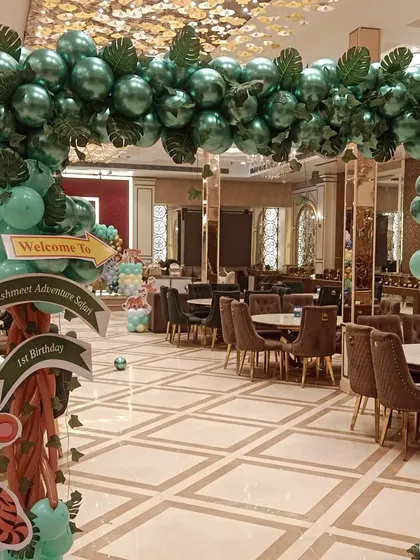 A grand jungle-themed entrance gate for a first birthday party. The balloon arch is made with chrome green balloons and artificial leaves, with a welcome sign to greet the guests.
