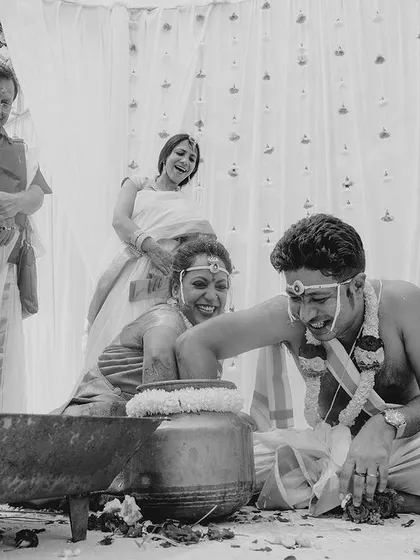 A joyous, black and white moment from a South Indian wedding game, capturing genuine laughter.