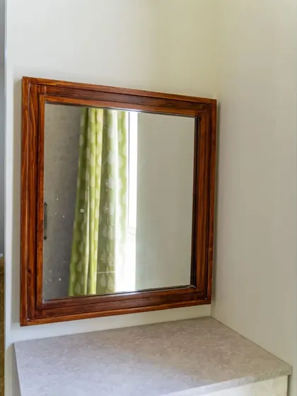 The dresser area within the guest room's walk-in closet, featuring a simple wooden-framed mirror and a laminate countertop.
