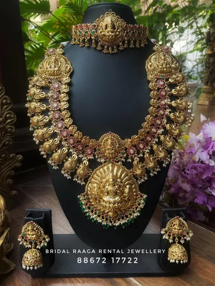 A beautiful temple jewellery set with a large, ornate pendant. The choker and haram both feature intricate carvings and are perfect for a traditional bridal look.
