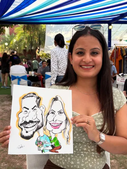 A couple poses with their caricature at an outdoor mela. My booth is a great attraction for festivals and fairs.