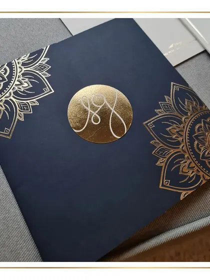 The centerpiece of this design is the custom monogram, foil-stamped in gold on a rich navy blue envelope. The mandala-inspired artwork adds a touch of traditional grandeur to the modern, clean aesthetic.