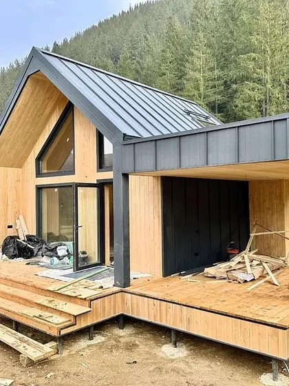 The structure of our A-frame home taking shape. This image shows the precision-engineered wooden frame and decking being assembled on-site, forming the foundation for a beautiful and durable holiday home.