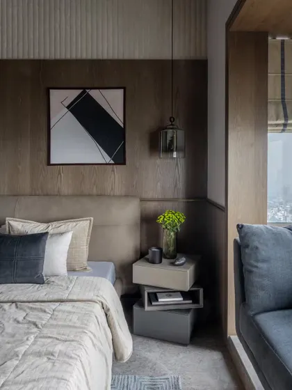 This bedroom combines a beautiful veneer bed-back with a fluted panel that extends onto the ceiling, adding depth and drama. The stacked bedside tables are a playful yet functional touch.