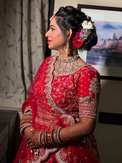 A side view of the bride, showing her complete look with the floral bun, elegant jewelry, and flawless makeup.