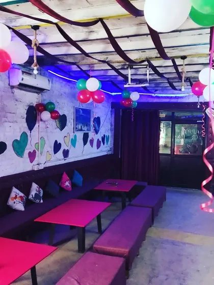 This image shows how I can decorate an indoor cafe space for a party using simple balloon bunches and streamers on the ceiling to add color and fun.
