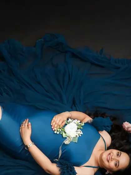An aerial view of a mom-to-be lying down, her blue gown spread out like water around her. This creative angle offers a unique and beautiful perspective on maternity.