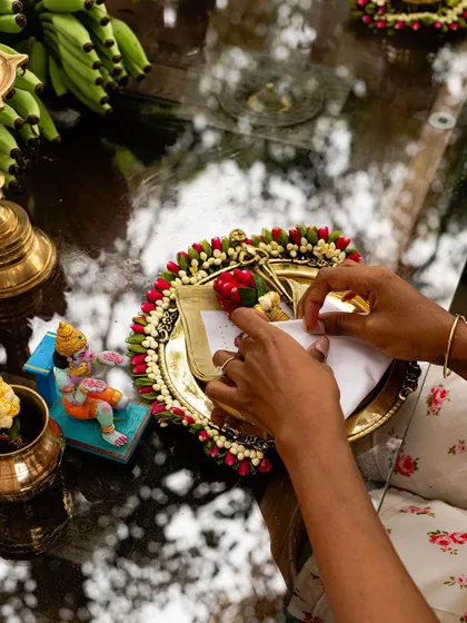 A moment of creation at our workshop. Here, a participant is carefully preparing a traditional offering on a brass plate, surrounded by fresh flowers and bananas.