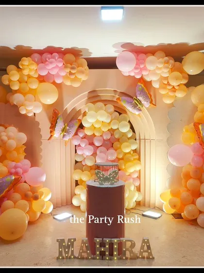 Mahira's third birthday was a dreamy butterfly party with a soft orange and pink color palette. The balloon arches create a beautiful frame around the central cake display.