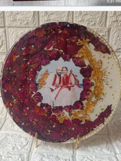 This round plaque showcases a wreath of preserved red rose petals and golden kaleere accents. The couple's photo is placed in the center, creating a classic and romantic wedding keepsake.