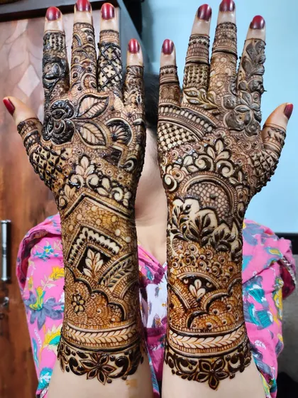 A bold and beautiful design with intricate patterns covering the hands and arms. The red nails provide a lovely contrast.