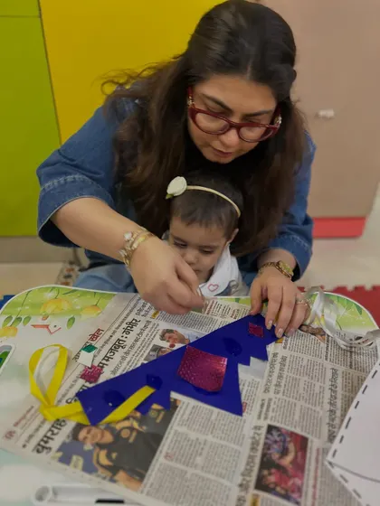 A mother guides her child in decorating a paper crown, combining crafting with imaginative fun.