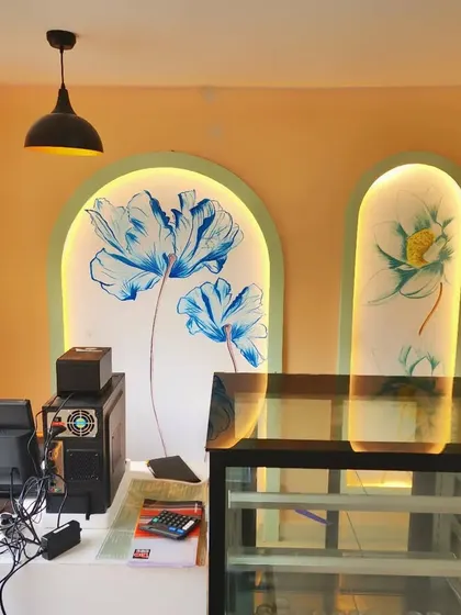 The counter area at Essence Cafe, featuring two of our hand-painted floral murals. Set within backlit arched niches, these pieces add a soft, artistic touch to the service point.