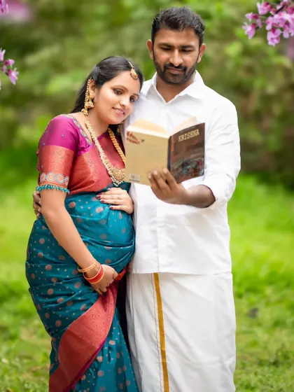 A sweet moment between a couple, reading a book together outdoors, dressed in traditional South Indian attire.
