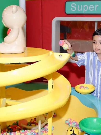 A boy plays with the ball drop toy located near the pretend supermarket.
