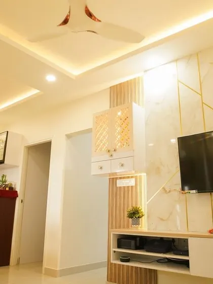 A wide view of the living and dining area, showcasing the cohesive design language with marble, gold, and wood elements used throughout the TV unit and dining display.