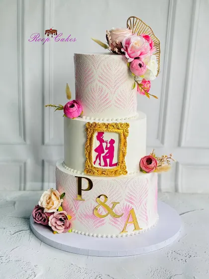 I love telling a love story through cake. This stunning three-tier engagement cake features a romantic proposal silhouette inside a golden frame, delicate stencil work, and beautiful florals, capturing the magic of a "yes" moment.