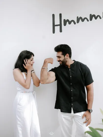 A playful pre-wedding photo where the bride-to-be is amazed by the groom's biceps.