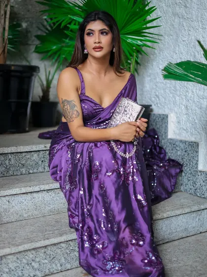 A glamorous shot of a model in a sequined purple saree, taken against a simple background to make the outfit stand out.