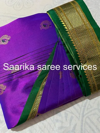 A classic Paithani-style saree with a purple body and green border, pleated and ready for a traditional event.