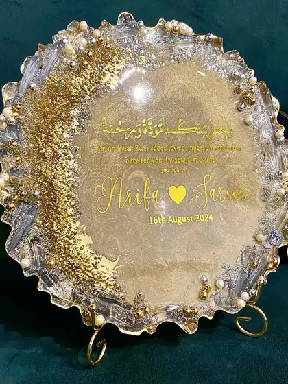 A custom engagement plaque with a scalloped edge, featuring the couple's names and wedding date. The gold and white resin is embellished with pearls and crystals for a celebratory feel.