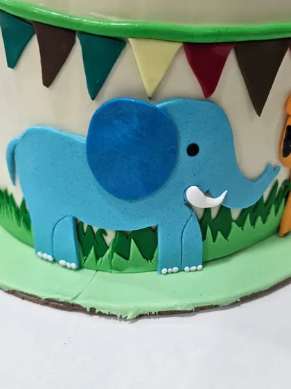 An adorable blue elephant fondant appliqué. This technique is perfect for adding multiple characters to a themed cake without overcrowding the top.