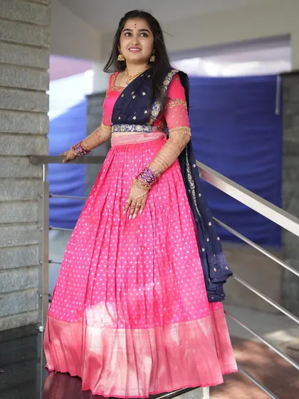 The bride posing on a staircase, showing the full length and rich colors of her custom Langa Dhawani.