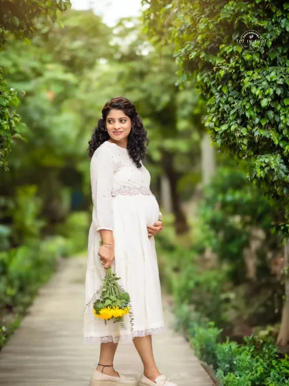 A charming outdoor portrait of a mom-to-be holding a bouquet of sunflowers, adding a bright and cheerful touch.
