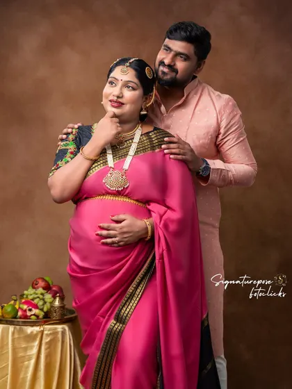 A classic pose for a traditional couple's maternity shoot, highlighting their bond and cultural attire.