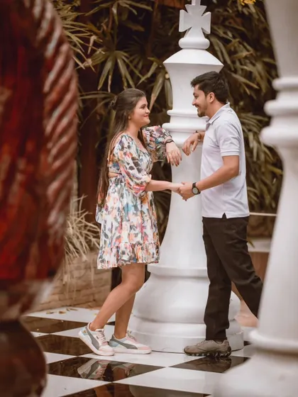 A romantic moment on the giant chessboard, with the couple holding hands. This shot combines fun and romance in a very unique setting.