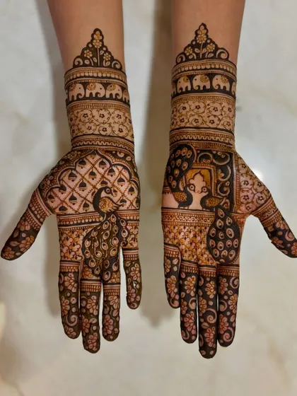 Nikita's engagement mehendi, featuring regal peacocks on the palms and elephant motifs on the wrist bands, blending traditional symbols with intricate patterns.