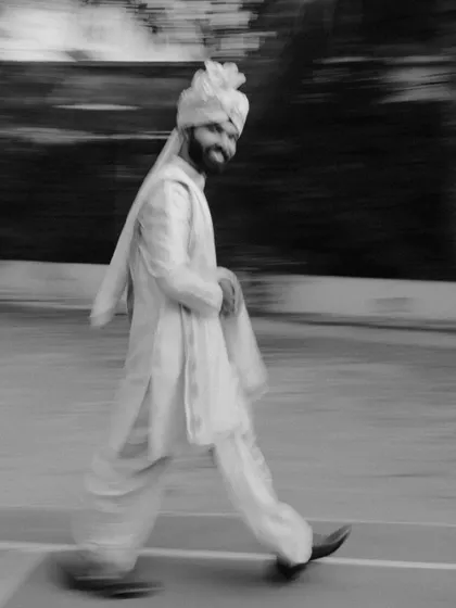 A creative motion-blur shot of the groom walking, capturing his joyful energy in black and white.
