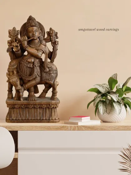 A 24-inch wooden Lord Krishna statue with a brown finish, styled in a modern interior setting to show its versatility as a decorative and spiritual object.