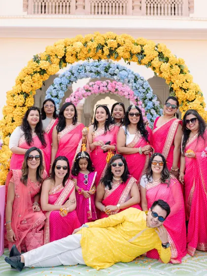 The groom joins the bride squad for a fun photo, playfully lying at their feet, adding a touch of humor to the group portrait.