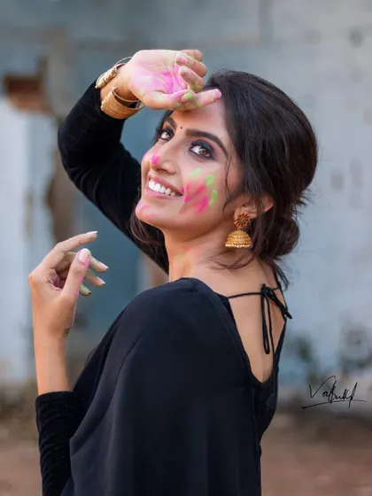 The pure joy of Holi captured in a candid moment. This portrait focuses on the vibrant colors and the model's infectious smile, blending traditional festival fun with a contemporary fashion aesthetic in a black saree.