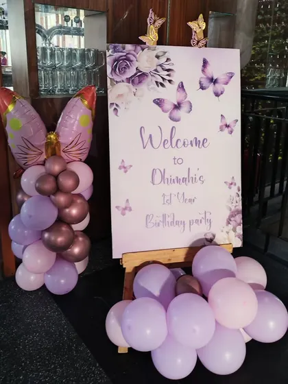 A custom welcome sign for a butterfly-themed first birthday party, with a matching balloon arrangement.