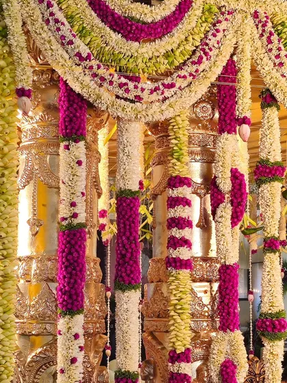 A close-up of intricate floral garlands used in a Muhurtha Mantapa. The combination of white, pink, and green flowers showcases the detailed artistry of our floral designers.
