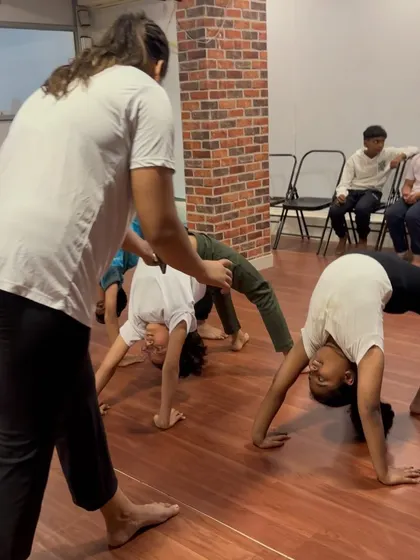 I guide two students in Chakrasana (Wheel Pose), helping them find the right alignment and push-off.